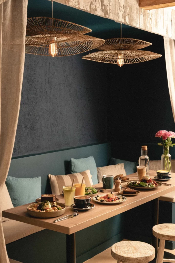 Coin brunch cosy Marlette Abbesses avec assiettes gourmandes, café et jus frais sous luminaires design