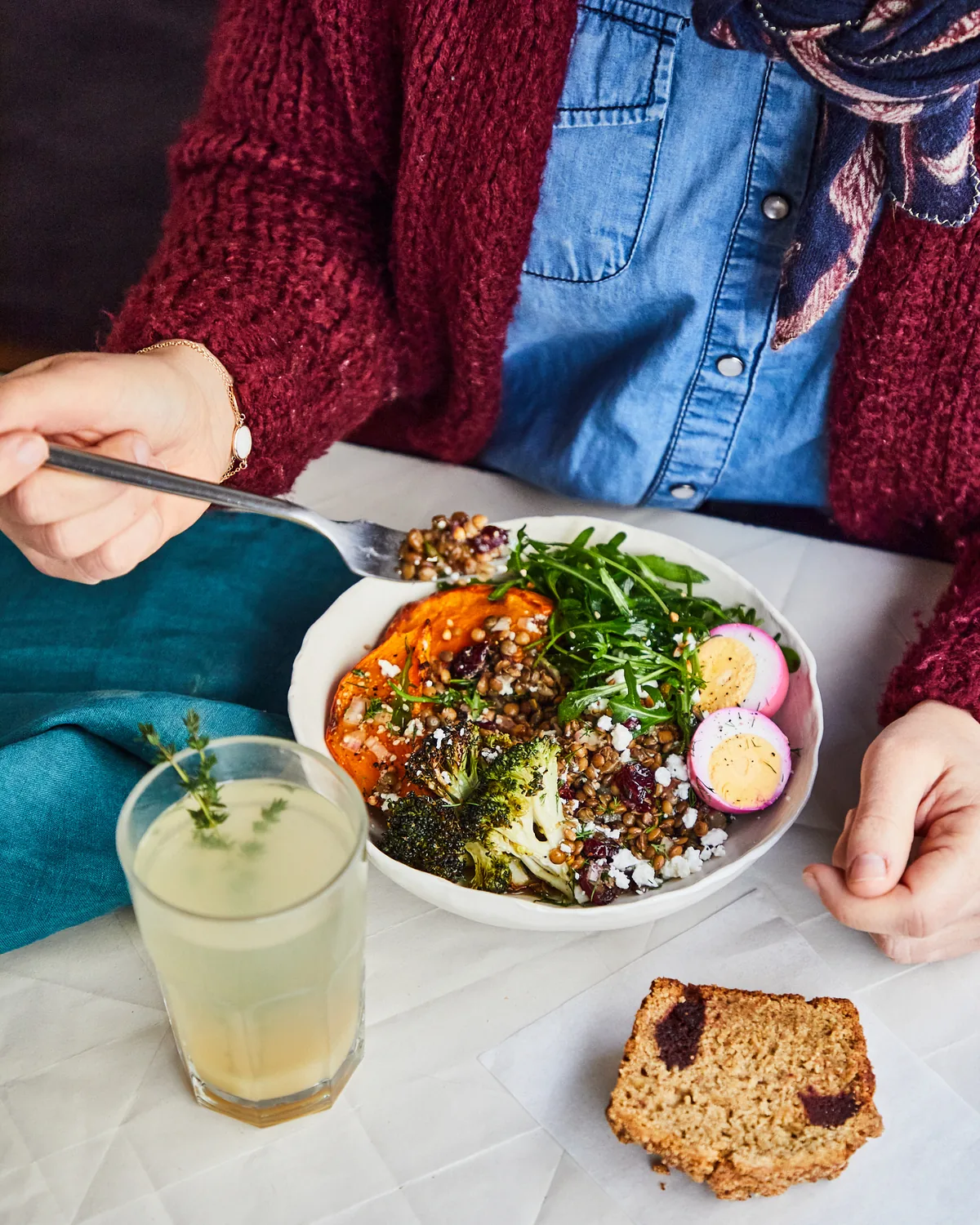 Großzügiger Brunch-Teller mit geröstetem Gemüse, Ei und Getreide, begleitet von einem frischen Zitronengetränk