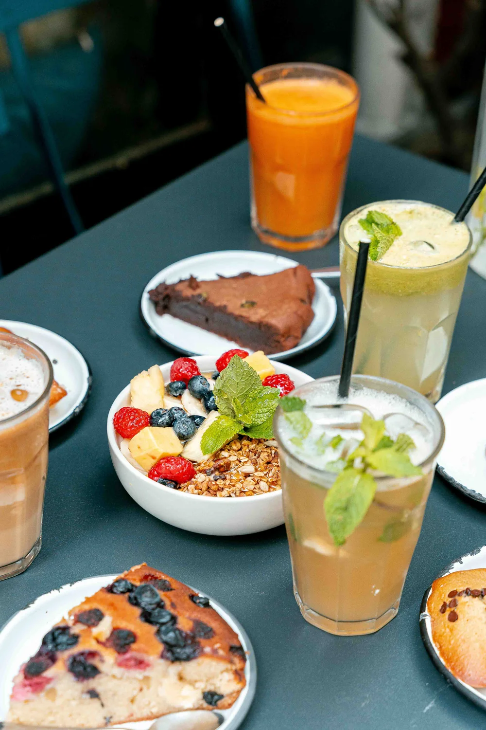 Table de brunch Marlette avec jus d'orange frais, cocktails à la menthe et bol de granola gourmand aux fruits rouges