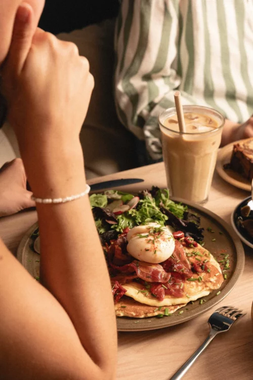 Plato de pancakes guarnecidos con jamón crudo y huevo poché, ensalada verde fresca, café con leche en Marlette Abbesses