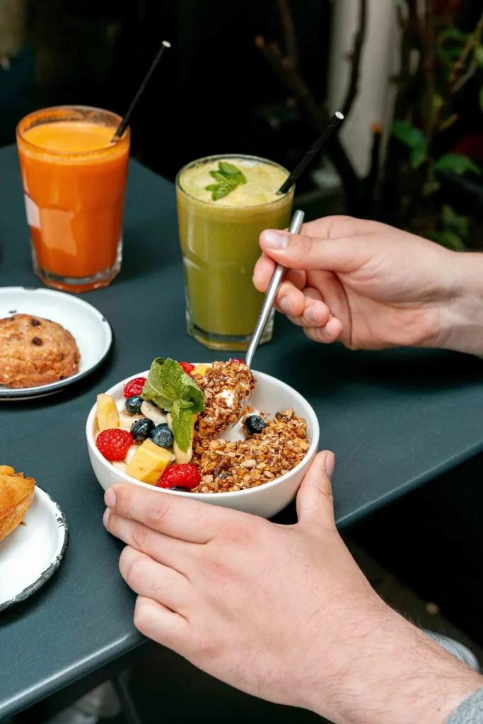 Bol de granola gourmand garni de fruits frais et yaourt, servi chez Marlette Abbesses avec jus frais et boisson verte