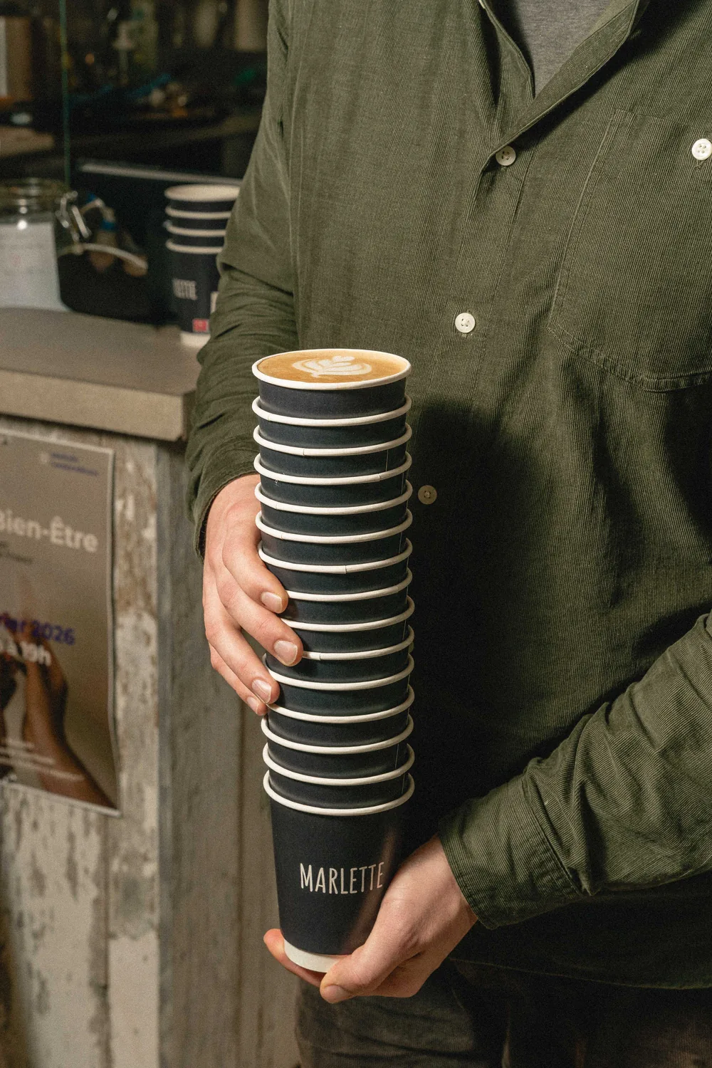 Gobelet réutilisable Marlette noir et blanc tenu en main, café latte avec latte art servi chaud à Paris