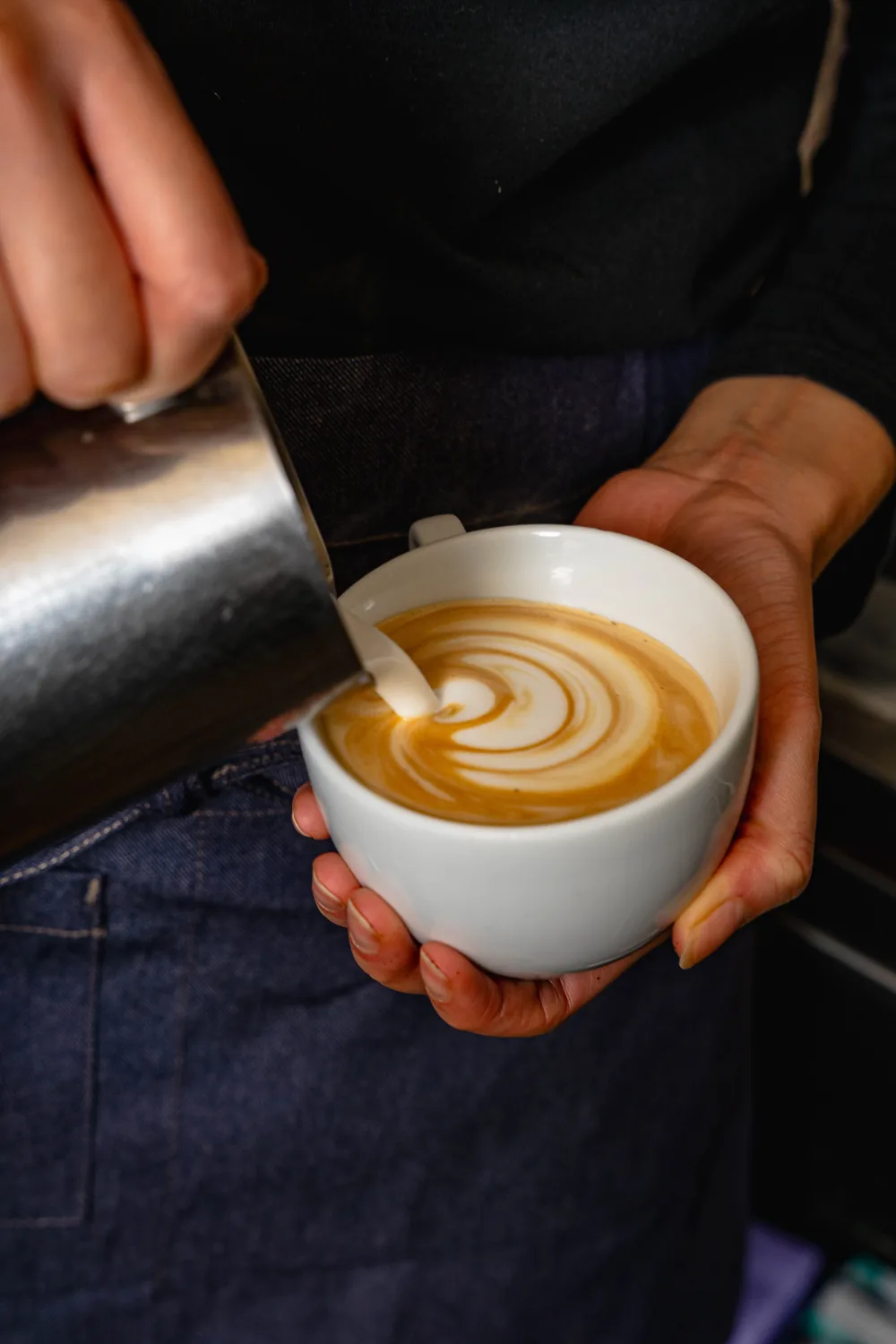 Tasse de café avec latte art en spirale, tenu dans les mains à Marlette Montmartre