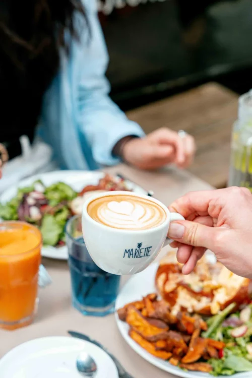 Tasse Marlette avec latte art cœur, entourée de brunch gourmand et jus frais
