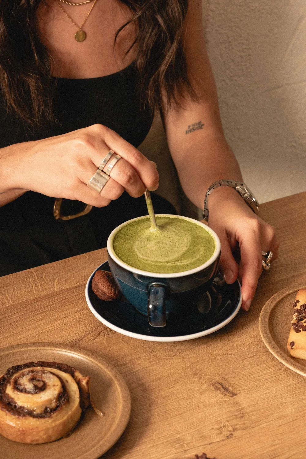 Femme dégustant un matcha latte gourmand aux côtés de viennoiseries fait-maison à Marlette Abbesses