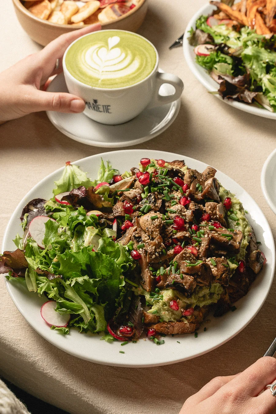 Assiette généreuse de toast à l'avocat avec salade fraîche et matcha latte chez Marlette