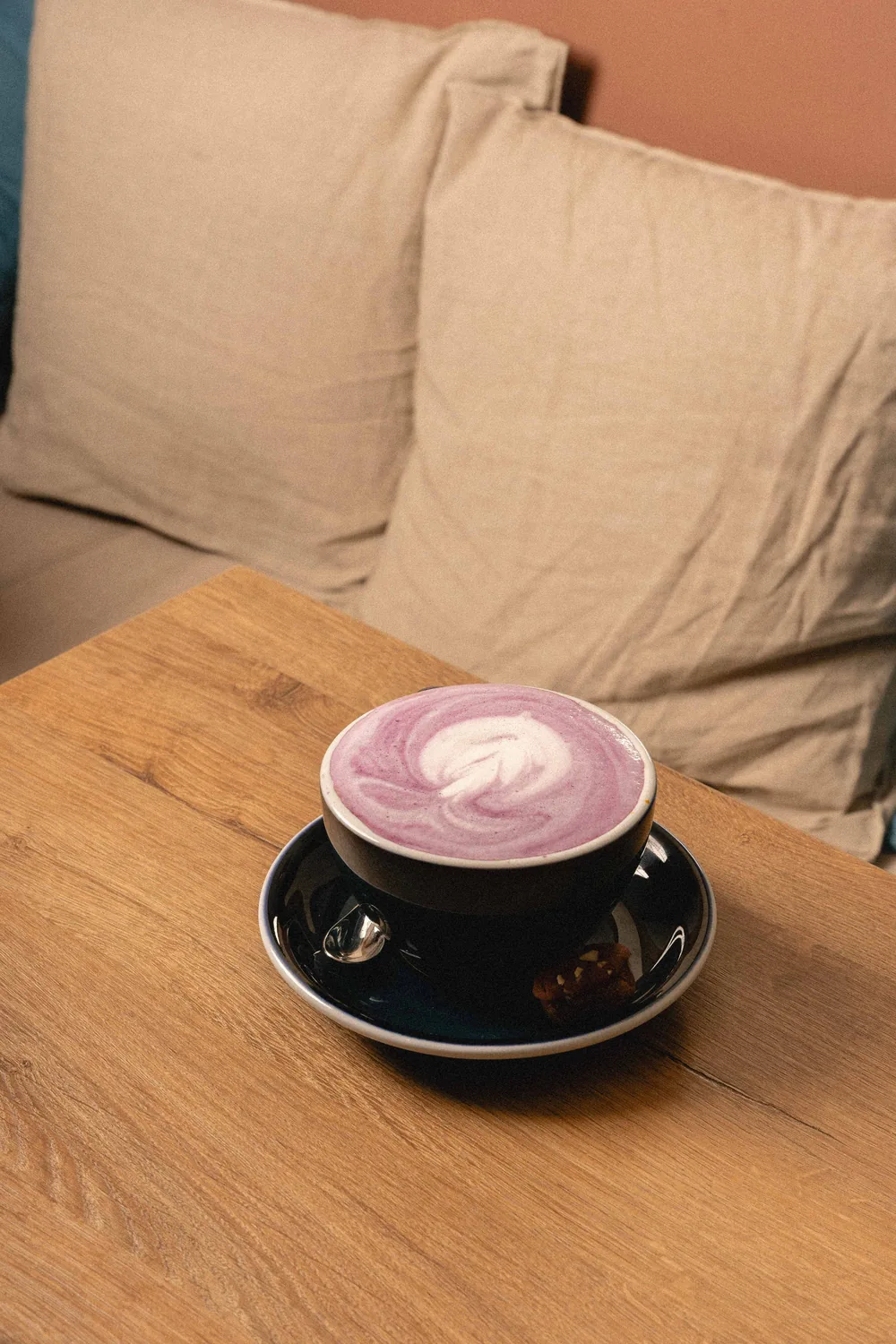 Taza de café rosa con latte art sobre mesa de madera, ambiente cálido en Marlette París