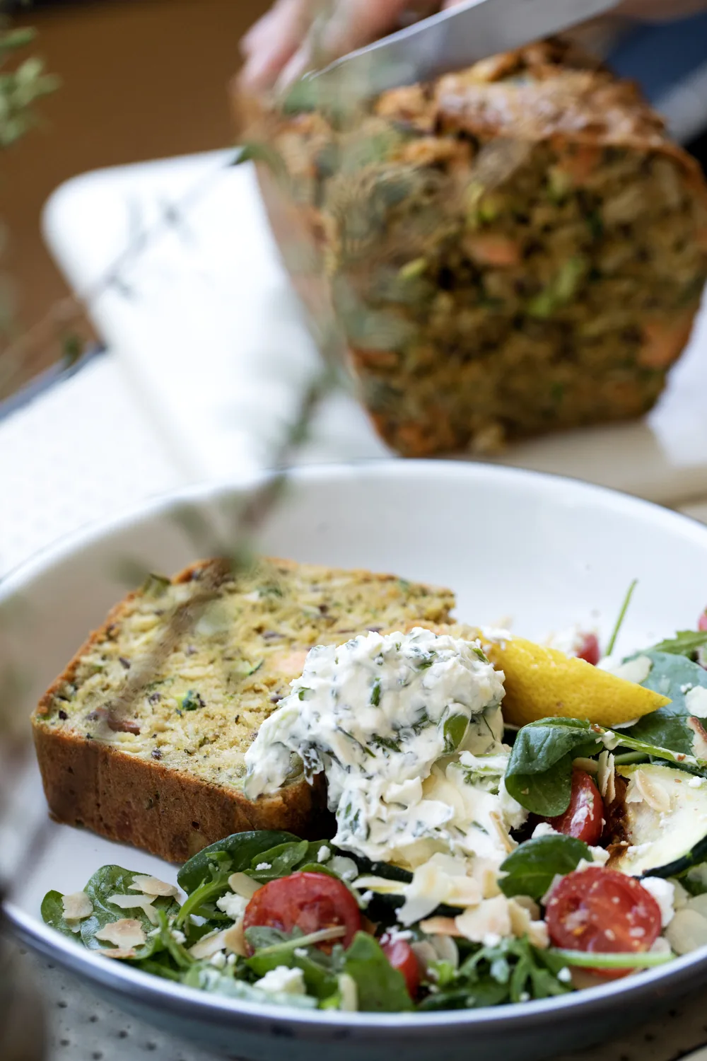 Scheibe frisches Kräuterbrot von Marlette, großzügig mit Frischkäse bestrichen, begleitet von einem genussvollen Salat
