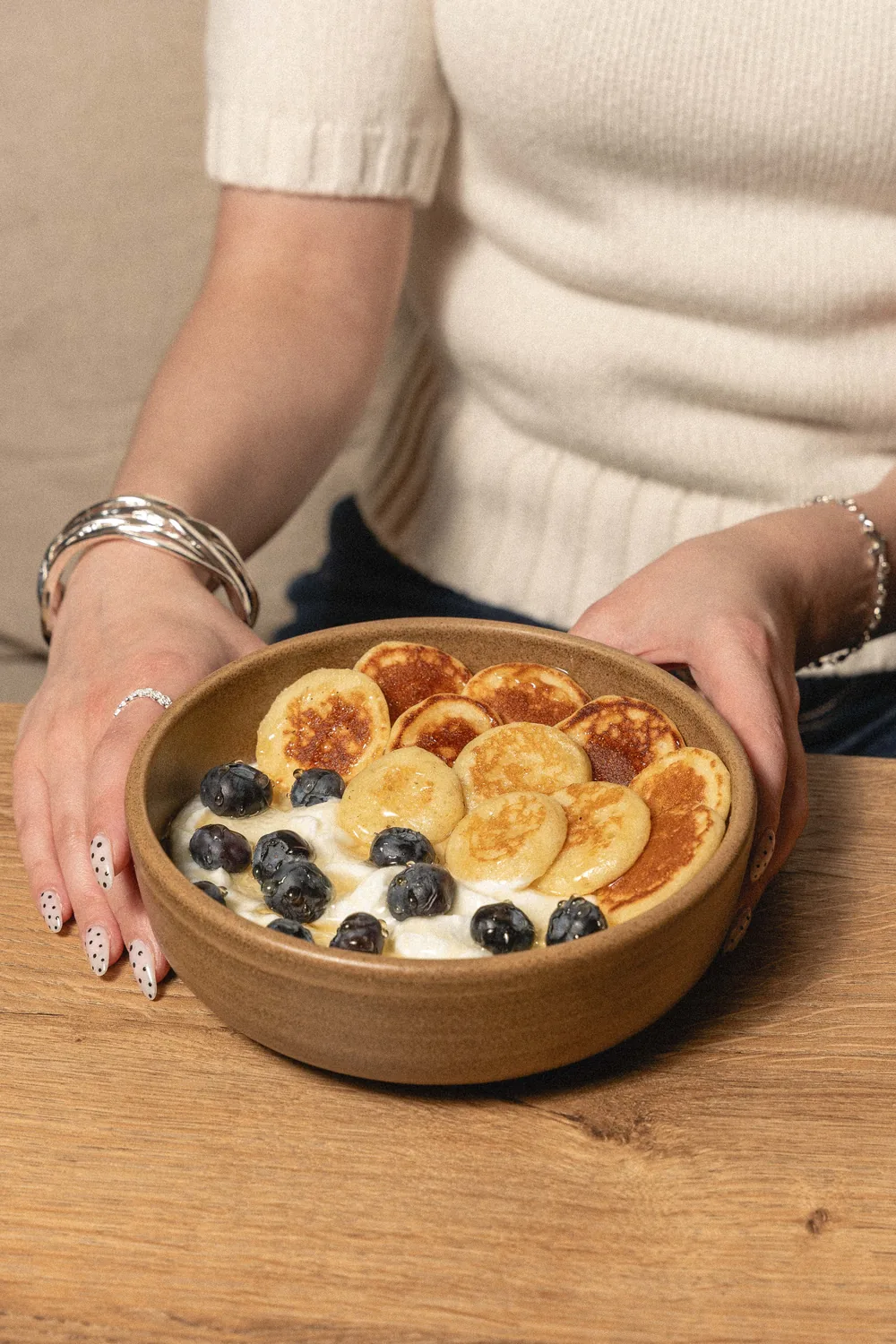 Wooden plate of indulgent pancakes topped with fresh blueberries and cream, a delicious breakfast at Marlette Abbesses
