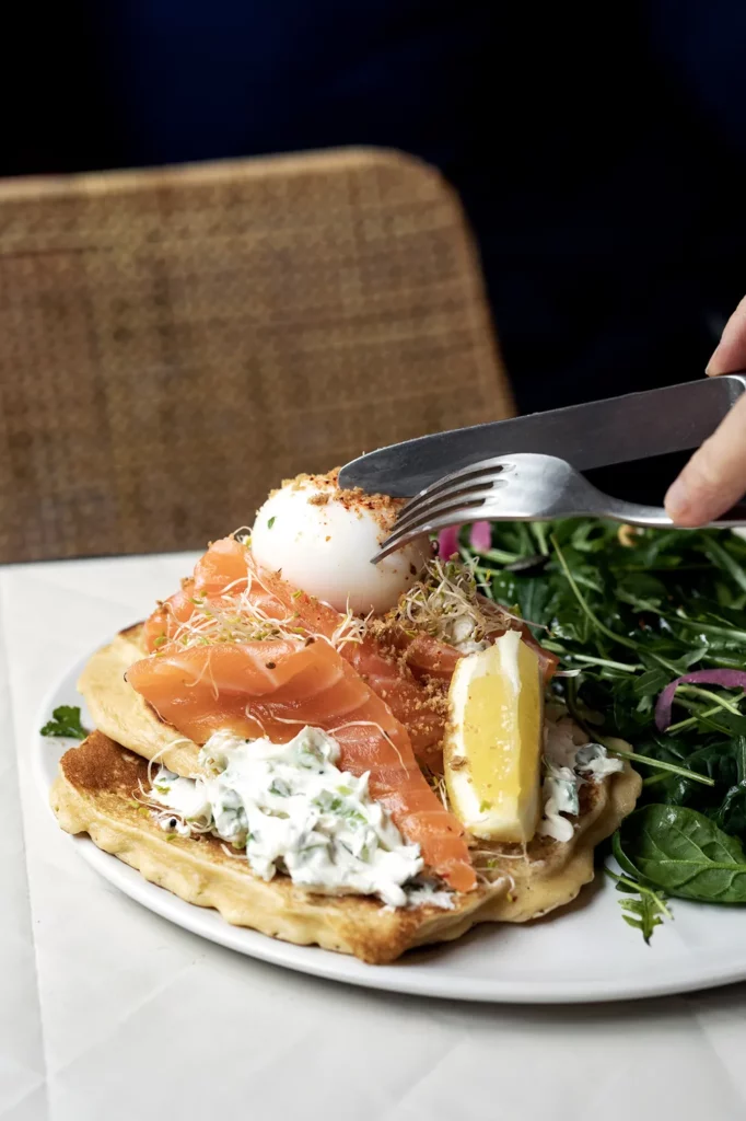 Pancakes moelleux garnis de saumon fumé, œuf poché et crème fraîche, servis à Marlette Abbesses