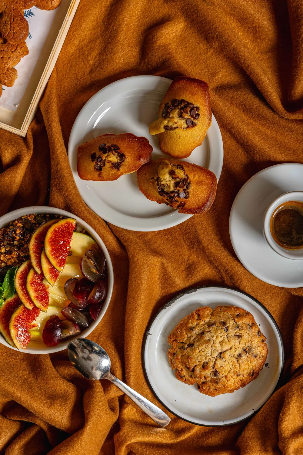 Plates of homemade Marlette pastries: chocolate madeleine, cookie and fresh fruit with coffee