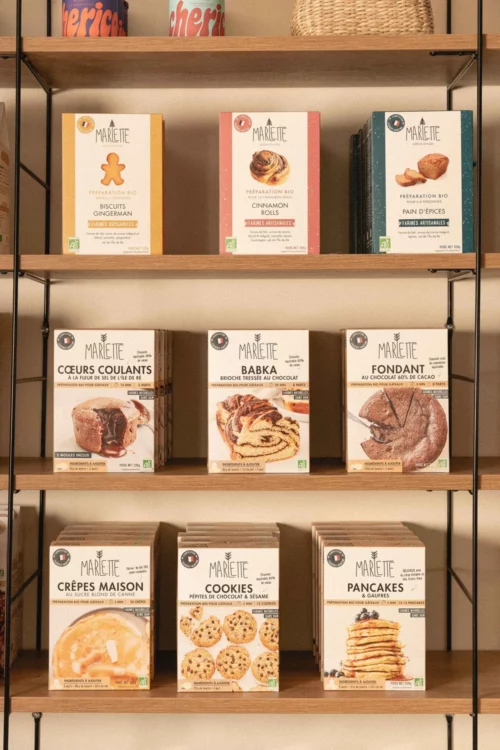 Étagère présentant les préparations pâtissières bio Marlette : biscuits gingerman, cinnamon rolls, pain d'épices, cœurs coulants, babka, fondant, crêpes maison, cookies et pancakes