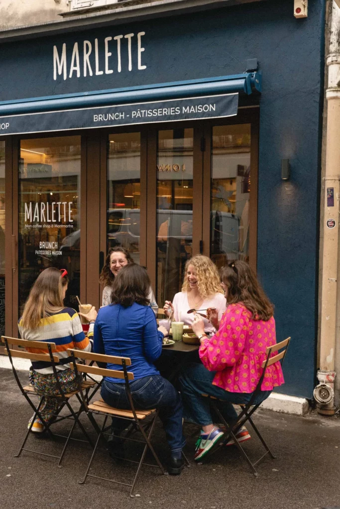 Groupe de quatre femmes dégustant leur brunch en terrasse devant la devanture bleue de Marlette à Paris
