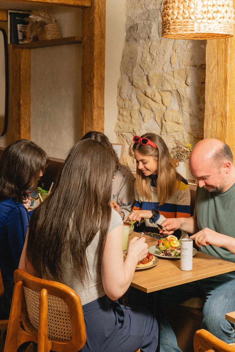 Famille partageant un repas convivial autour d'une table en bois dans l'ambiance chaleureuse et rustique de Marlette à Paris