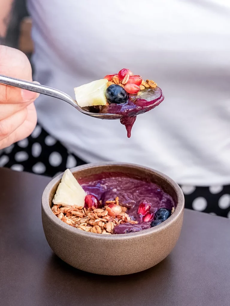 Cuillère prélevant une bouchée d'açai bowl garni de granola, myrtille et fleur comestible chez Marlette aux Abbesses