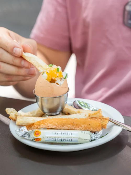 Cliente dégustant un œuf à la coque servi dans un verre avec des soldiers beurrés, Marlette coffee shop Pigalle Paris