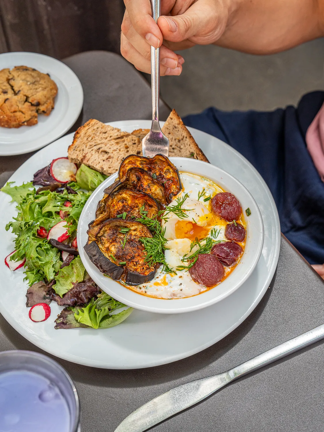 Client dégustant une assiette de brunch composée d'œufs, bacon croustillant et toast grillé, salade verte fraîche, chez Marlette Martyrs à Pigalle