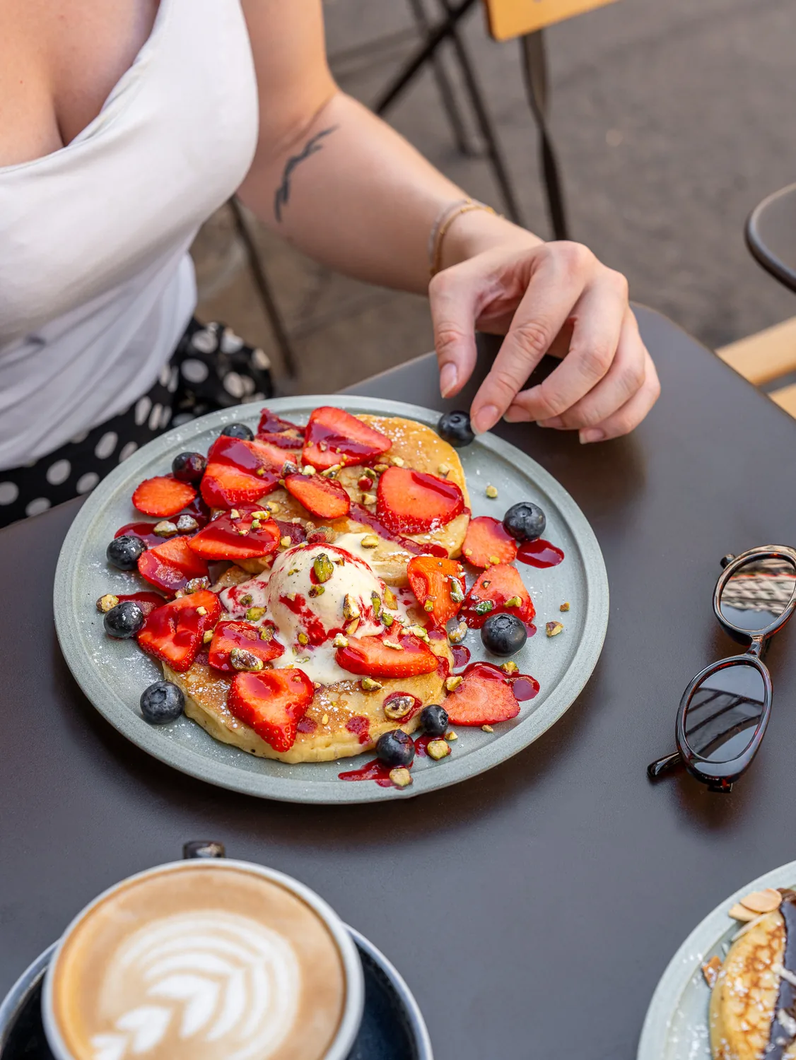 Assiette de pancakes garnis de fraises fraîches et myrtilles, accompagnée d'un cappuccino, à Marlette Abbesses à Montmartre