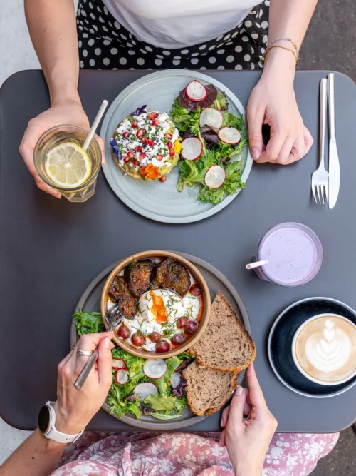 Deux clients partagent un brunch coloré avec œufs coques, avocado toast et salades fraîches au coffee shop Marlette Abbesses Montmartre