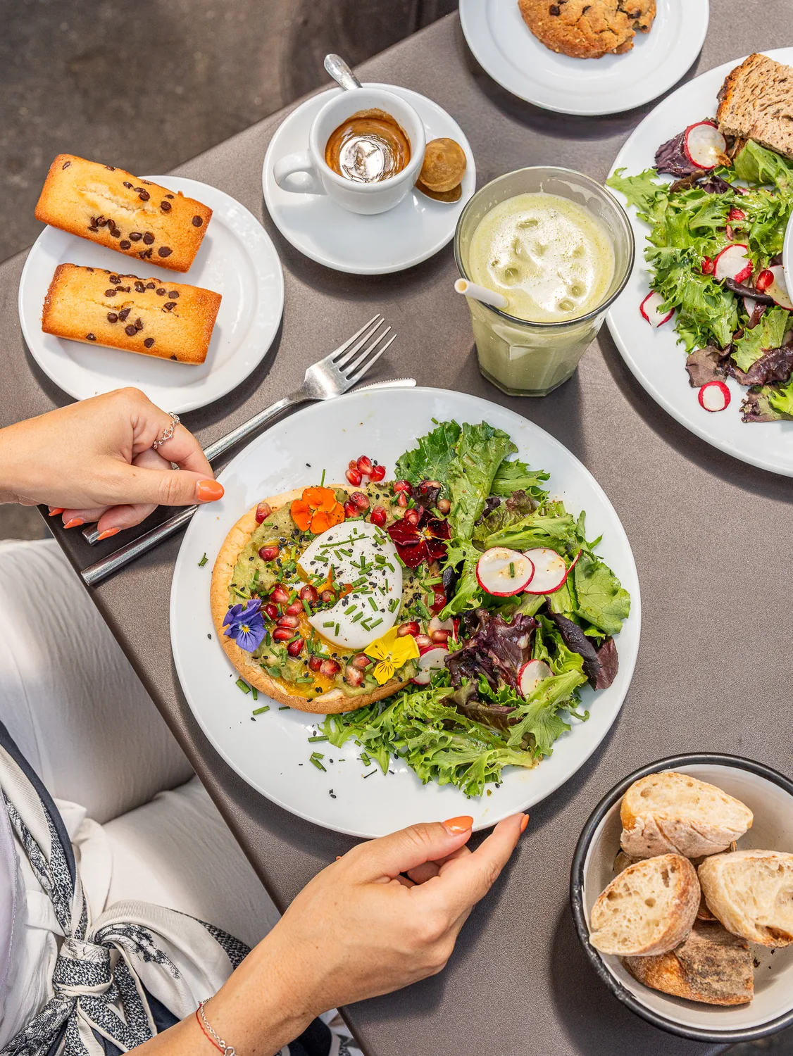 Cliente dégustant un toast garni d'œuf et de légumes frais avec salade, café et pâtisseries maison au coffee shop Marlette des Martyrs, Pigalle