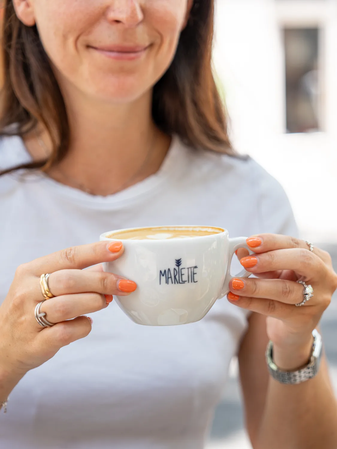 Cliente tenant un cappuccino Marlette avec latte art, au coffee shop des Martyrs à Pigalle, Paris