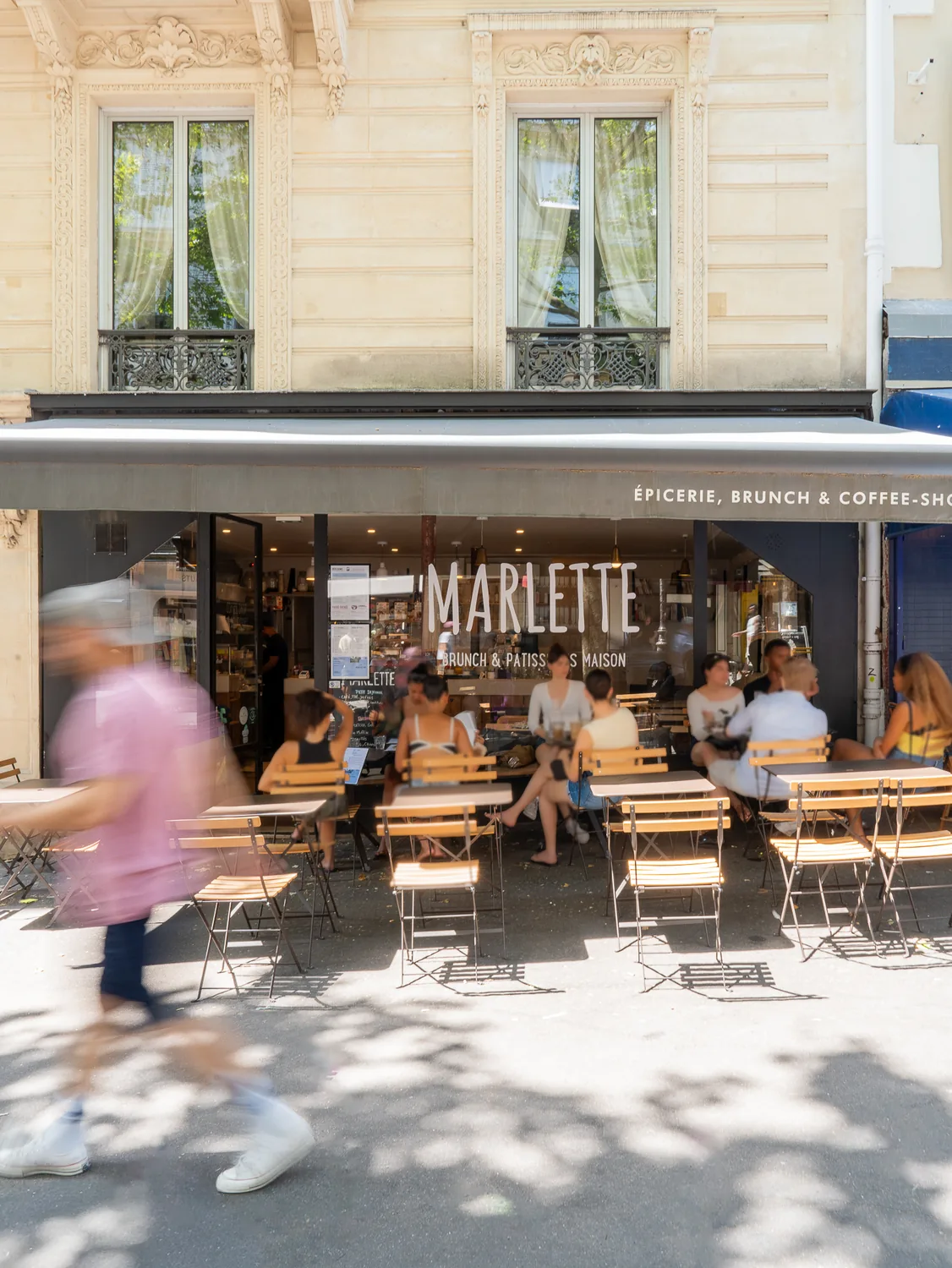 Façade du coffee shop Marlette avec terrasse animée, clients attablés en plein soleil, rue des Martyrs à Pigalle, Paris.