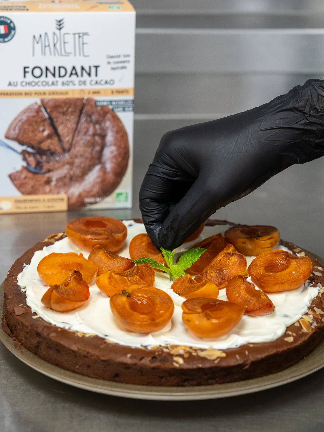 Gâteau fondant au chocolat garni de crème et d'abricots confits, présenté par un barista gantés noir chez Marlette aux Abbesses à Montmartre