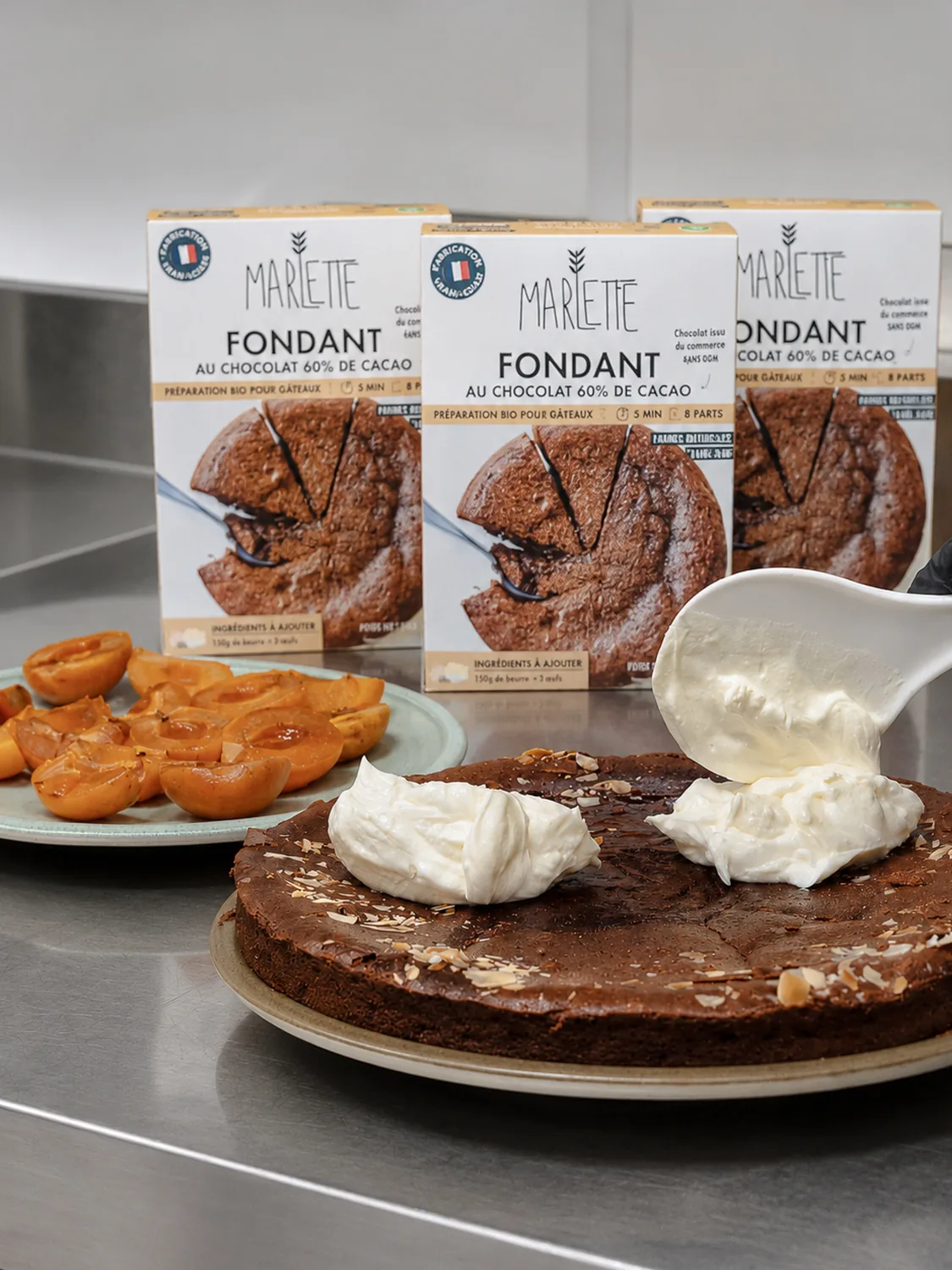 Fondant au chocolat maison garni de crème fraîche, entouré de boîtes de préparation pâtissière Marlette bio et de viennoiseries à la main. Montmartre, Abbesses.