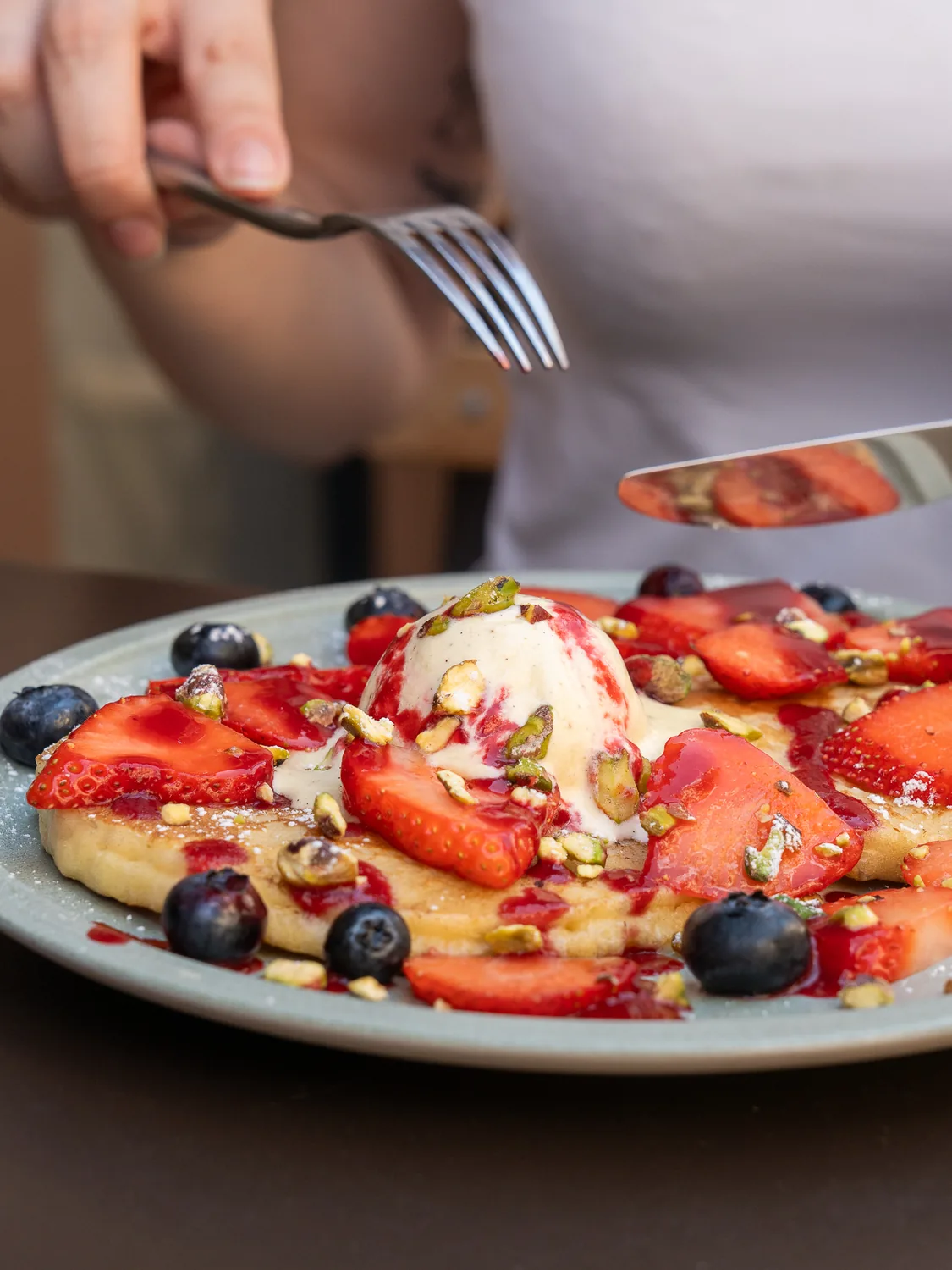 Assiette de pancakes garnis de fraises fraîches, myrtilles, glace vanille et pistaches concassées chez Marlette à Montmartre